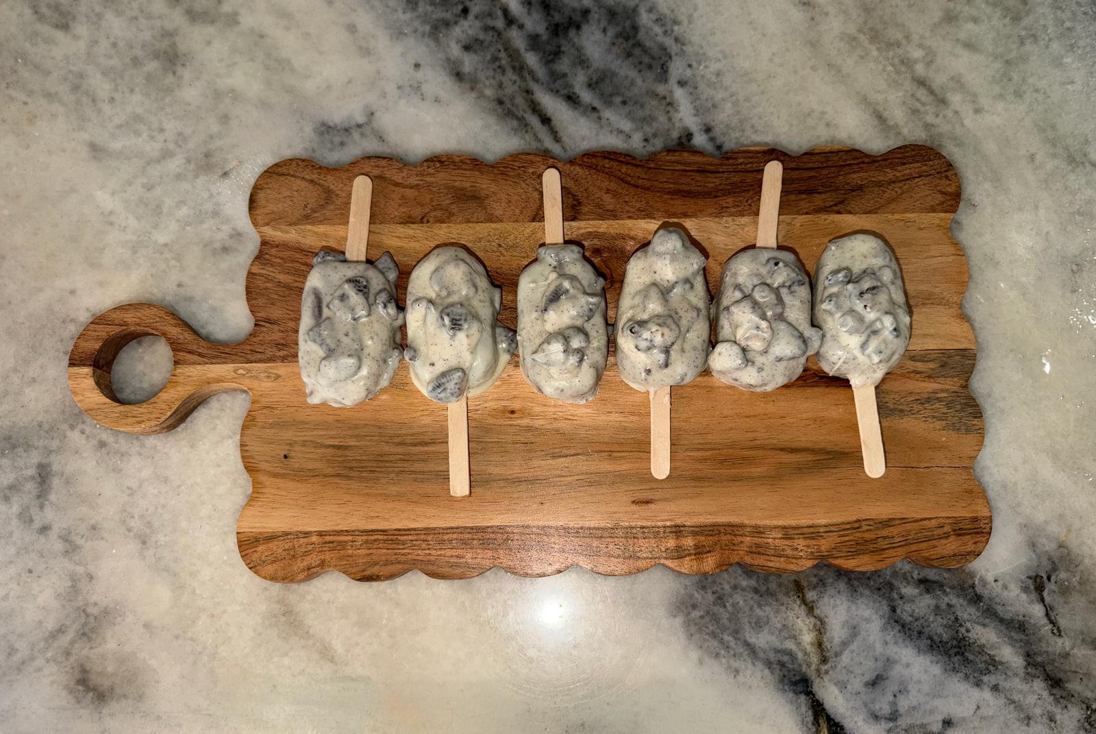 Cookies-and-cream cakesicles lined up on a board